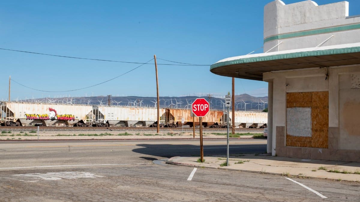 A stop sign beside an abandoned building and train in Mojave, CA.
