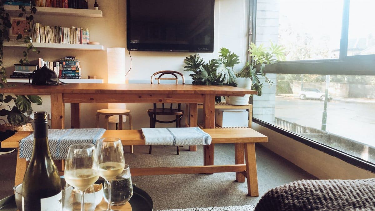 Stylish living room with wooden table, chairs, and wine in Potts Point apartment.