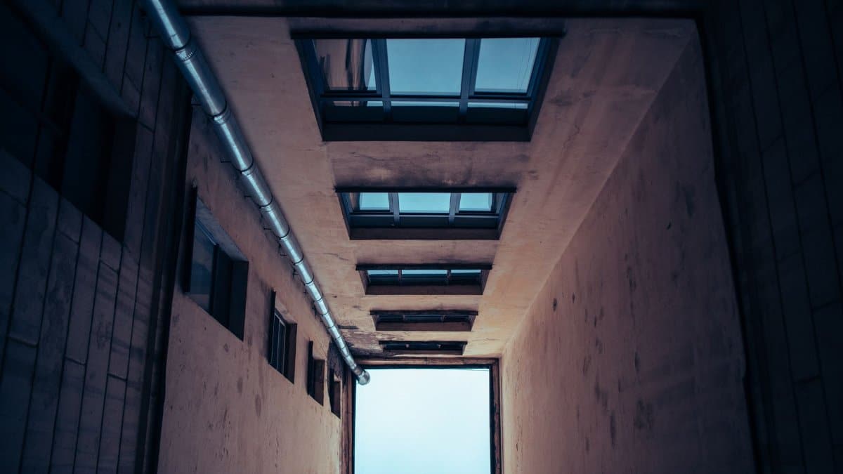 From below of narrow residential multistory house with many windows under cloudless sky