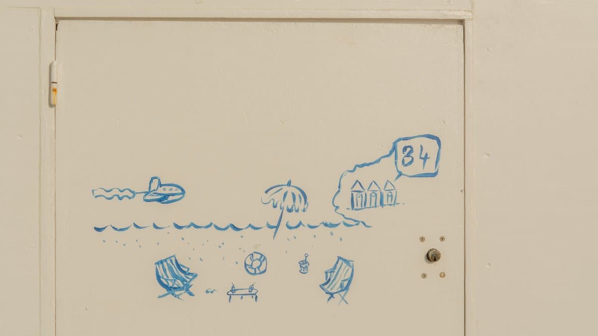 Simple beach-themed door art featuring palm tree, deck chairs, and ocean waves