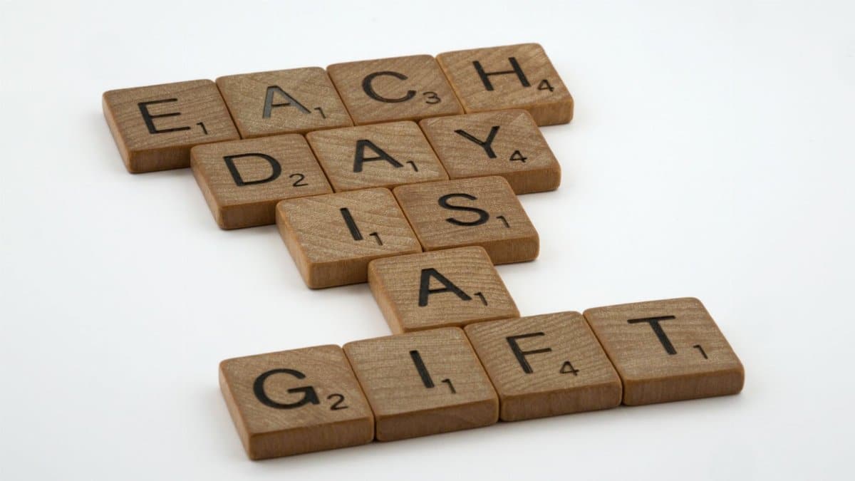 Scrabble tiles spelling 'Each Day is a Gift' on a white background, conveying positivity and inspiration.
