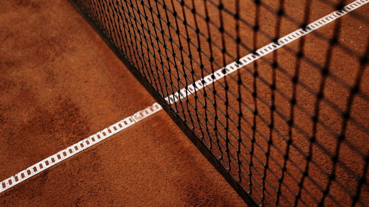 Detailed close-up of a clay tennis court featuring the net and white baseline.