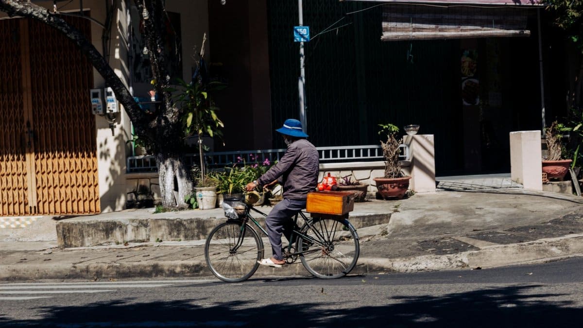 A cyclist rides through a sunny street in Kon Tum, Vietnam, capturing local life.