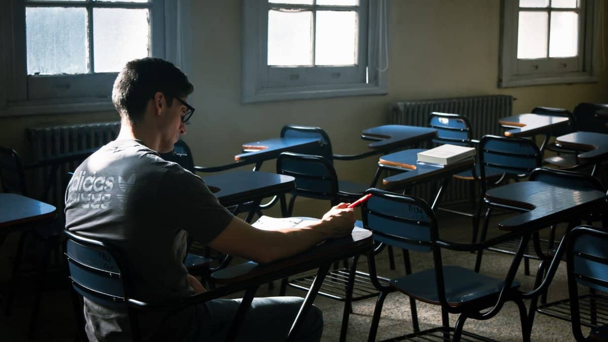 An empty classroom with a lone student using a phone, capturing a serene and contemplative atmosphere.