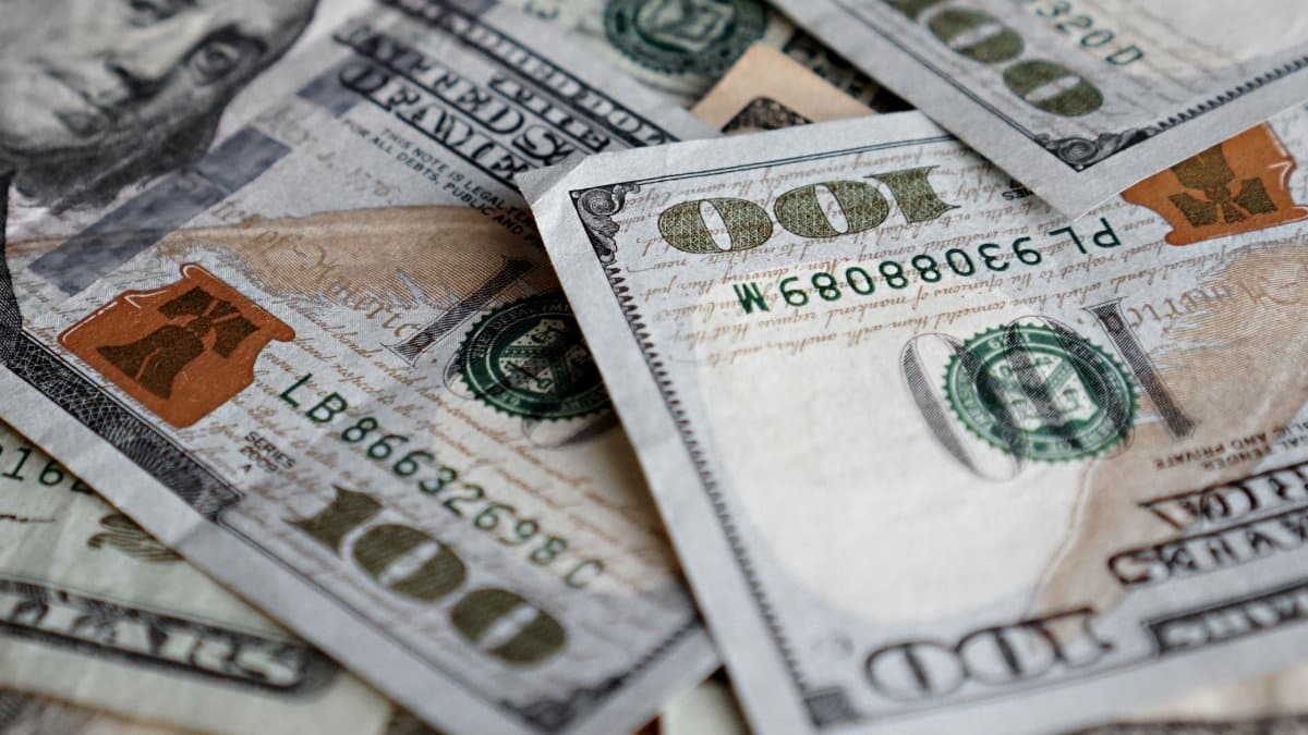 Stack of US dollar bills showing one hundred dollar notes prominently.