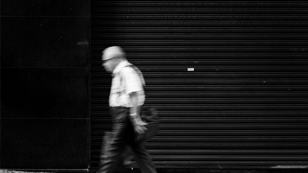 Blurred motion of an elderly man walking in Curitiba, Brazil, showcasing urban street photography.