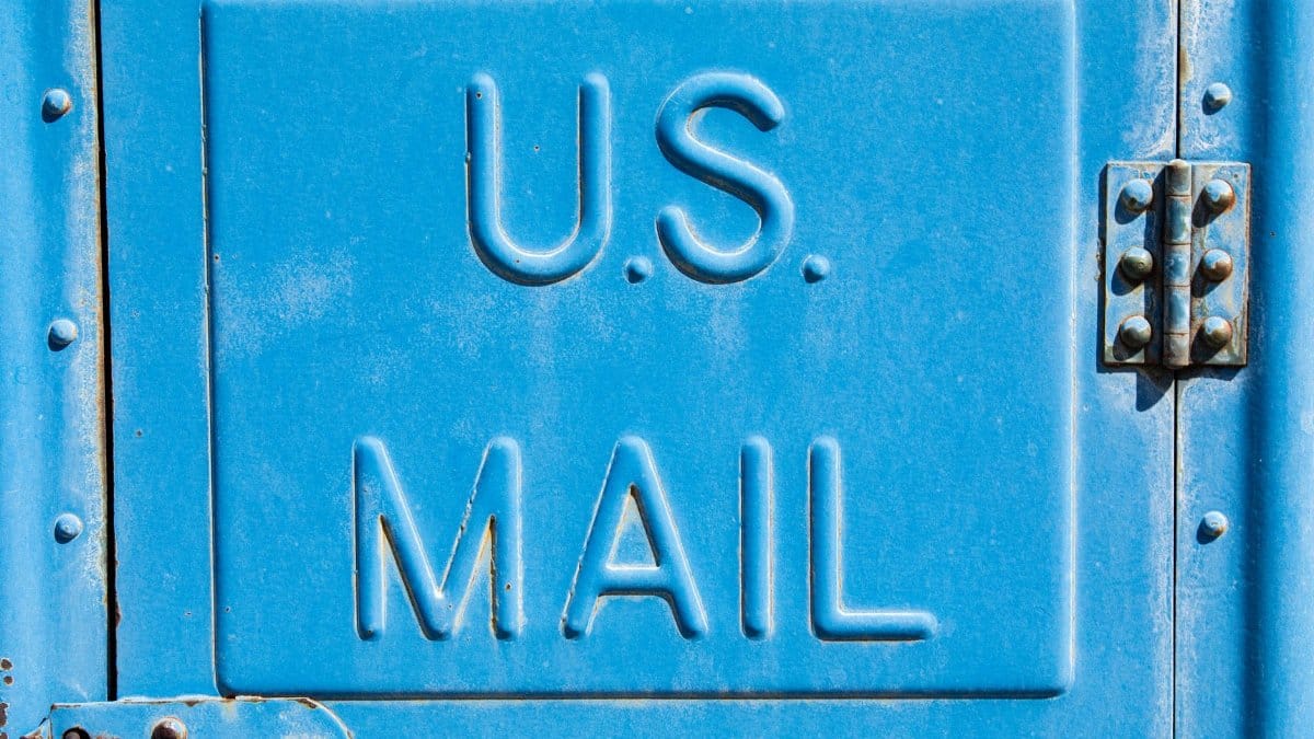 Detailed view of a classic blue US mailbox door with engraved letters in Florence, South Carolina.