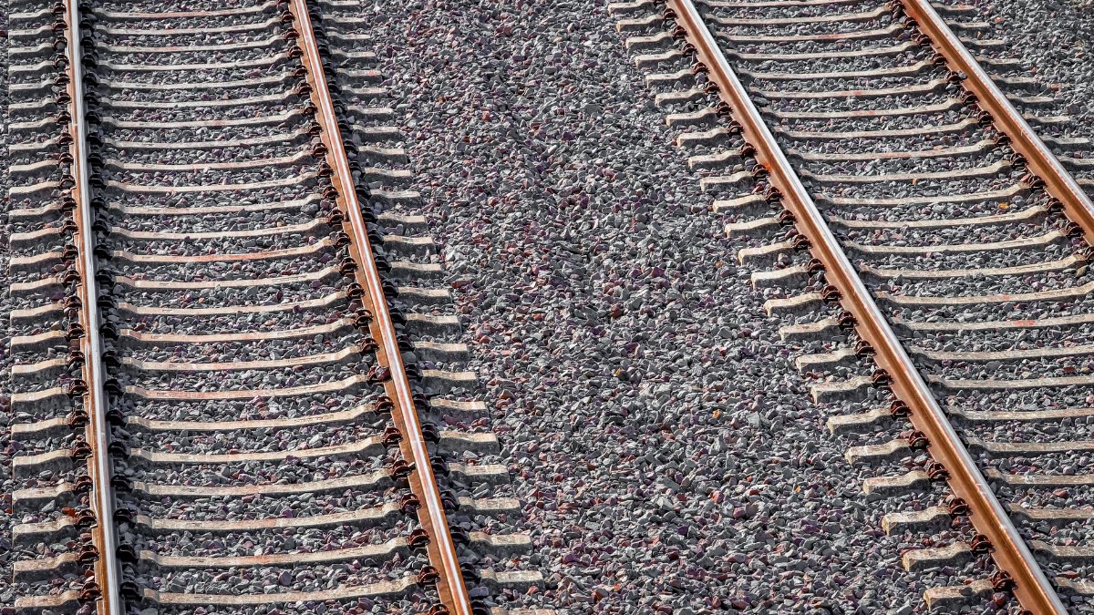 Two parallel railway tracks with rusty appearance captured under bright sunlight.