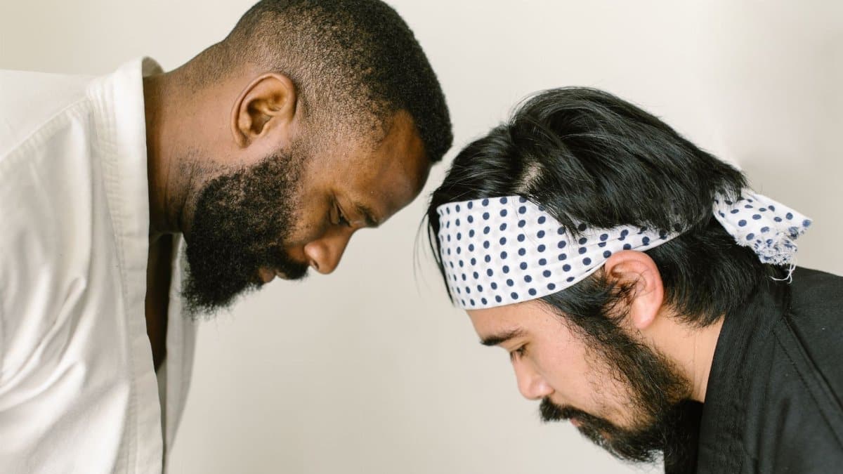 Two martial artists bow in respect to each other during training indoors.