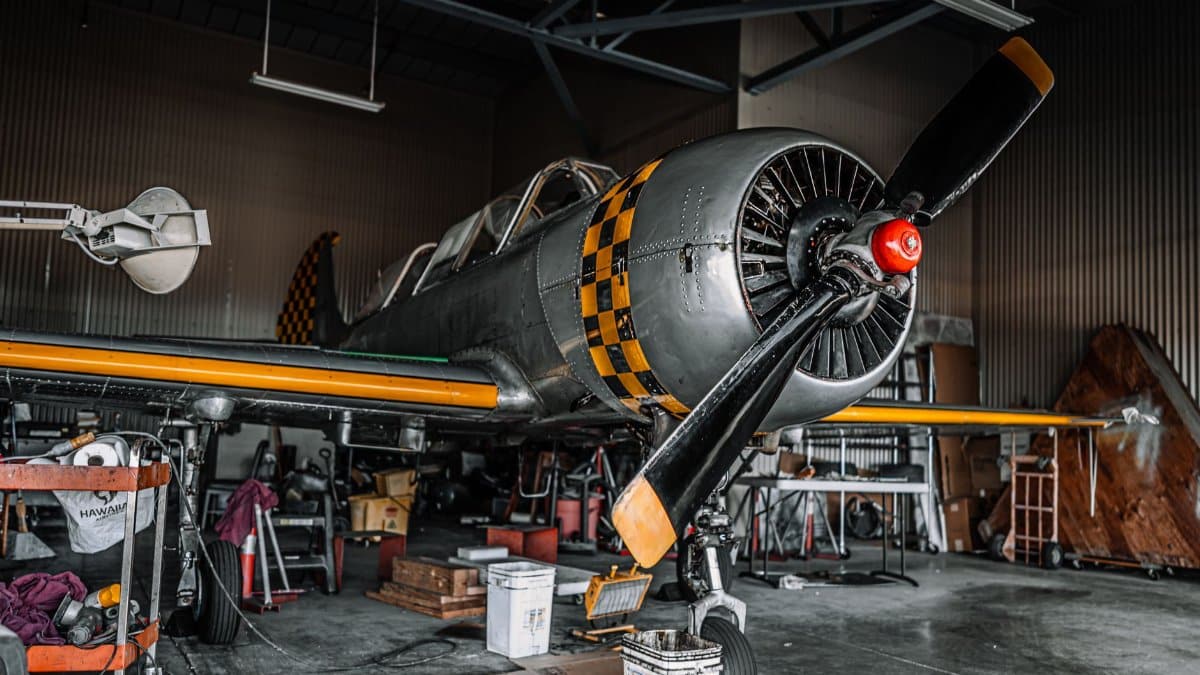 Old fashioned gray propeller jet parked for maintenance in modern spacious air shed