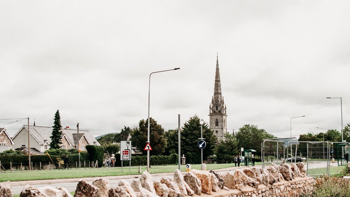 View of St Margaret's Church amidst a cloudy sky in Bodelwyddan, Wales, with greenery and rural charm.