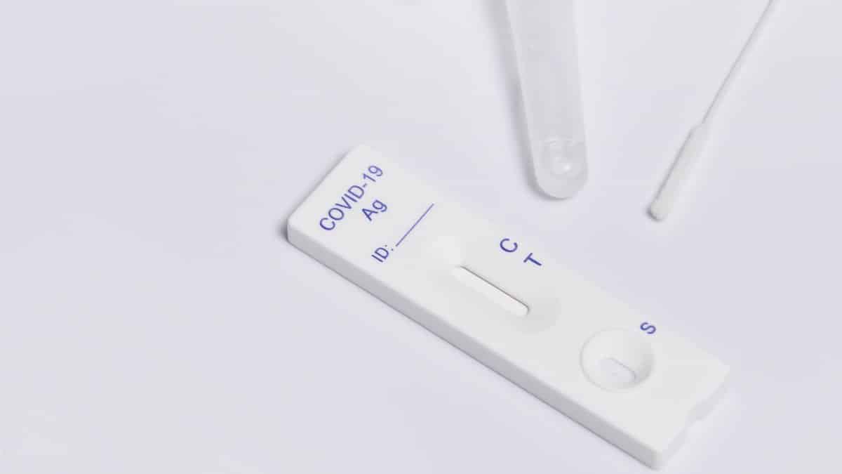Close-up of a COVID-19 rapid antigen test kit with swab on a white surface.