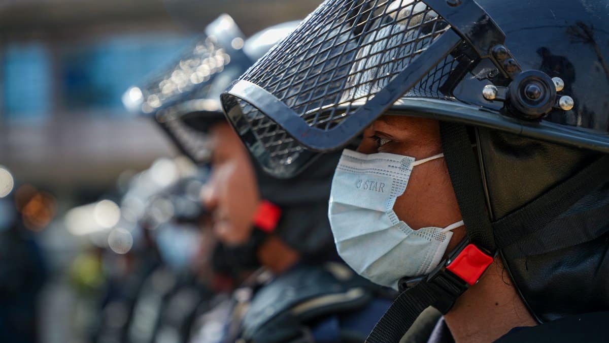 Close-up of riot police officers wearing face masks and helmets in an outdoor formation.
