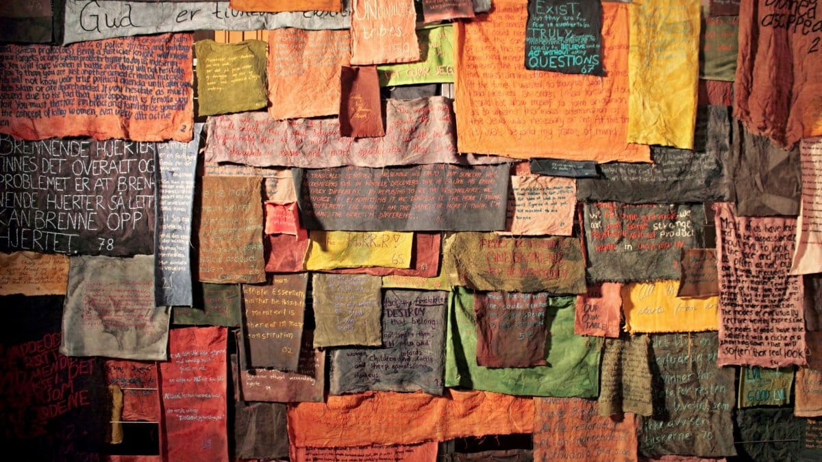 Vibrant cloth pieces with handwritten messages hung on a rustic wall, showcasing creativity.