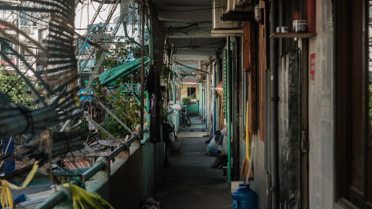View of a cluttered outdoor corridor in an urban apartment setting.