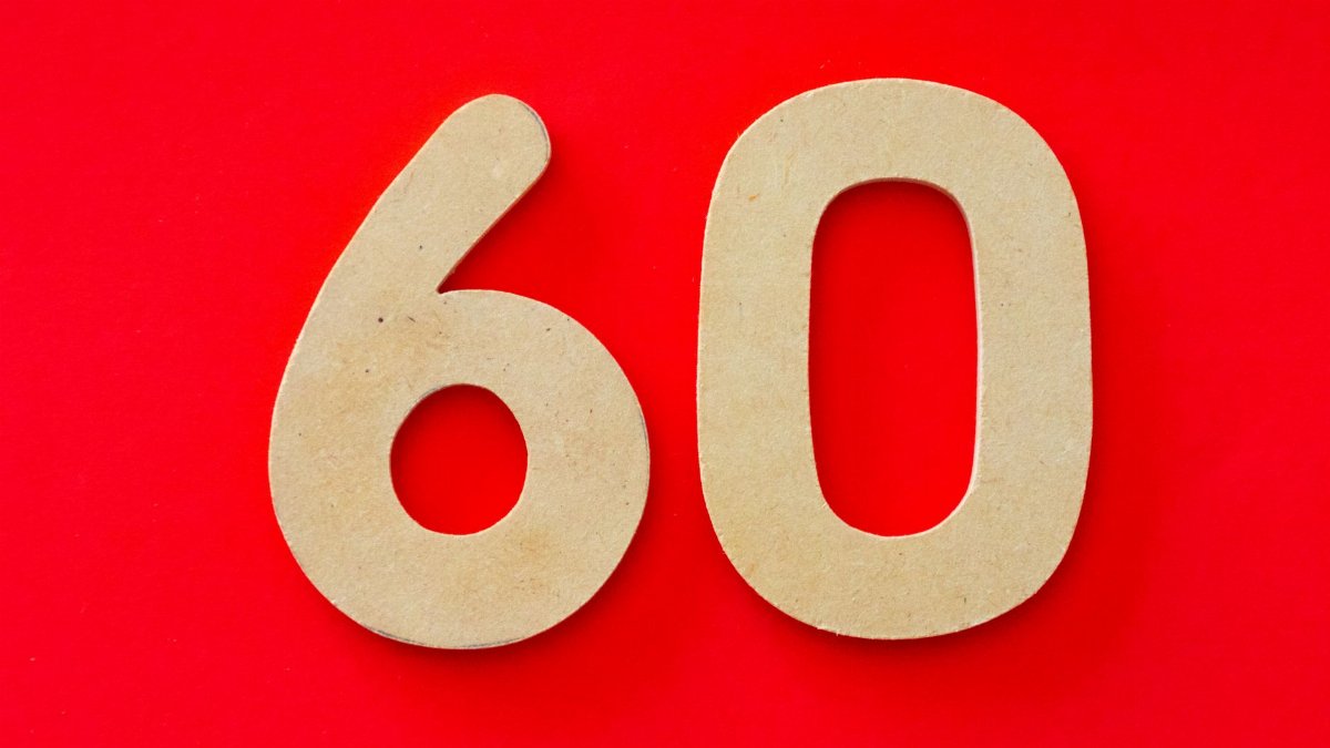 Wooden cutout of the number 60 displayed on a vibrant red background, ideal for milestones or celebrations.