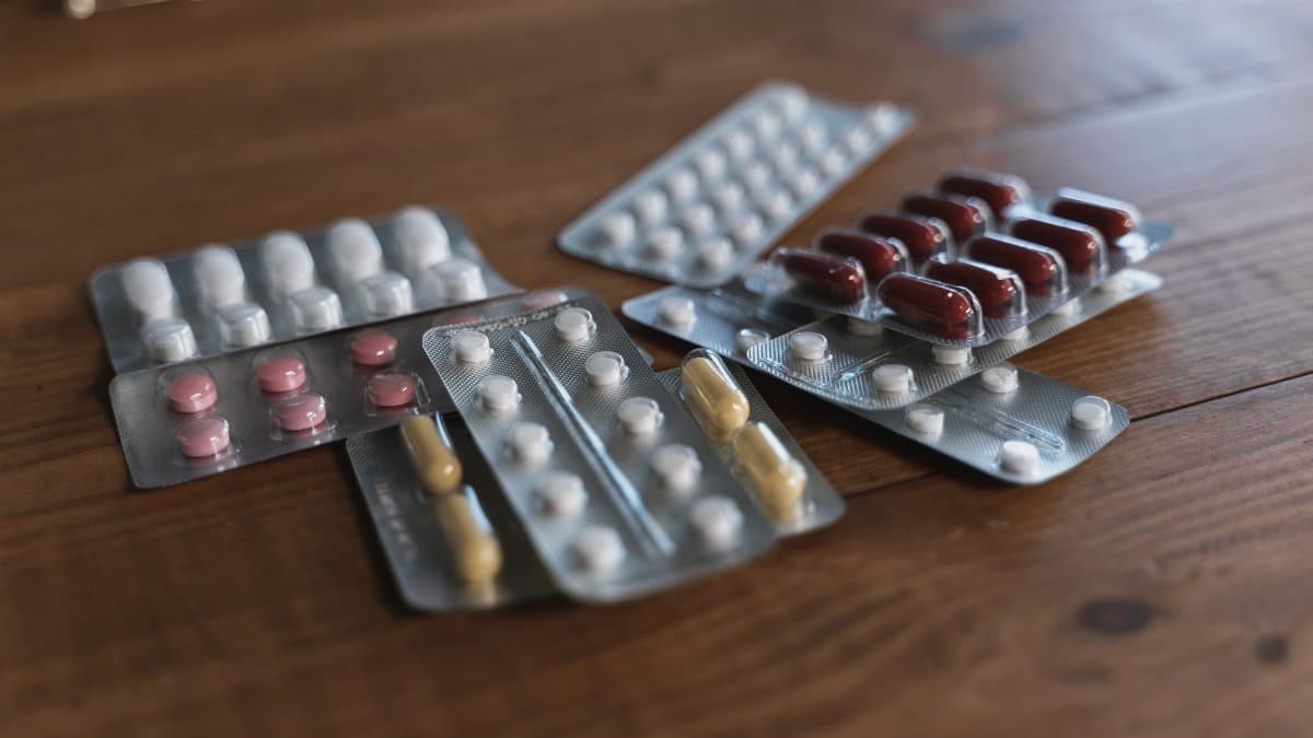 A variety of pills in blister packs displayed on a wooden surface. Ideal for health-related content.