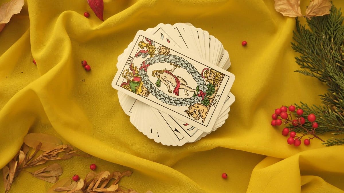 An artistic display of tarot cards on vibrant yellow fabric with decorative elements.
