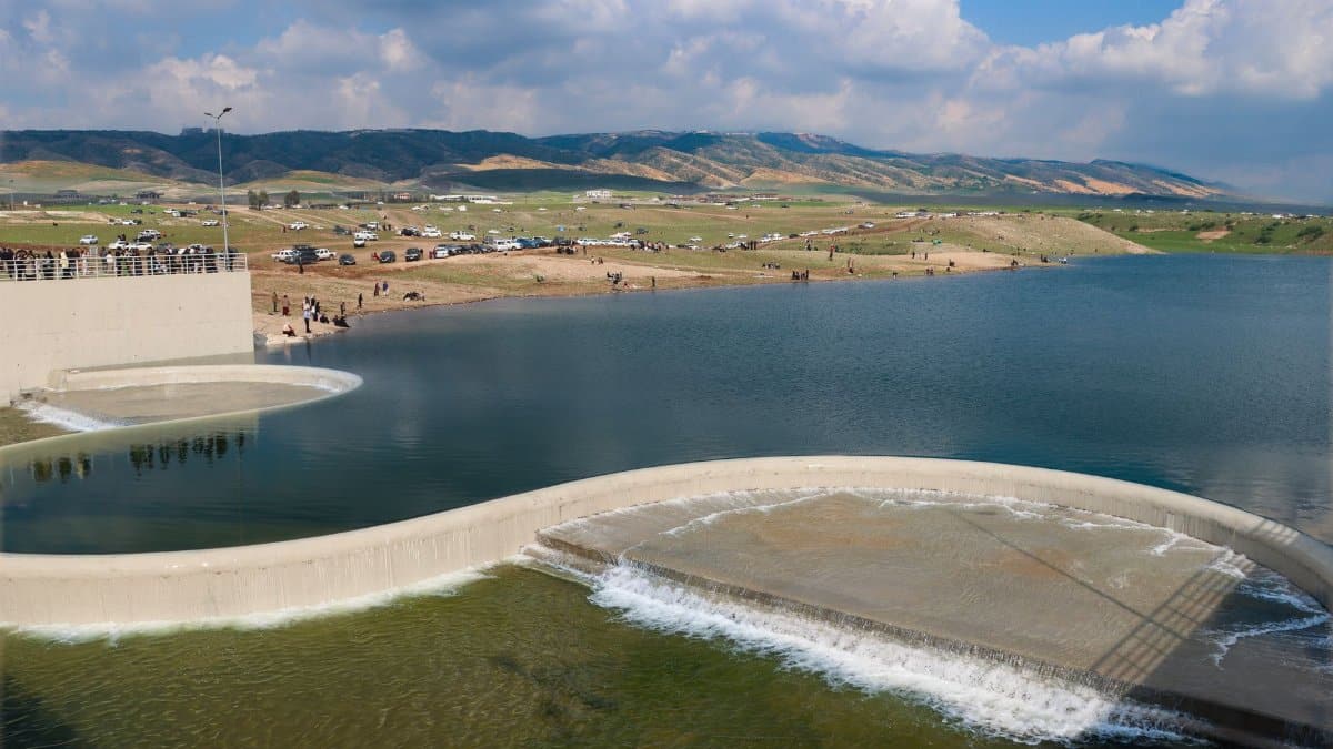 Skyline view of a reservoir with a scenic overflow spillway surrounded by hills and clear skies.
