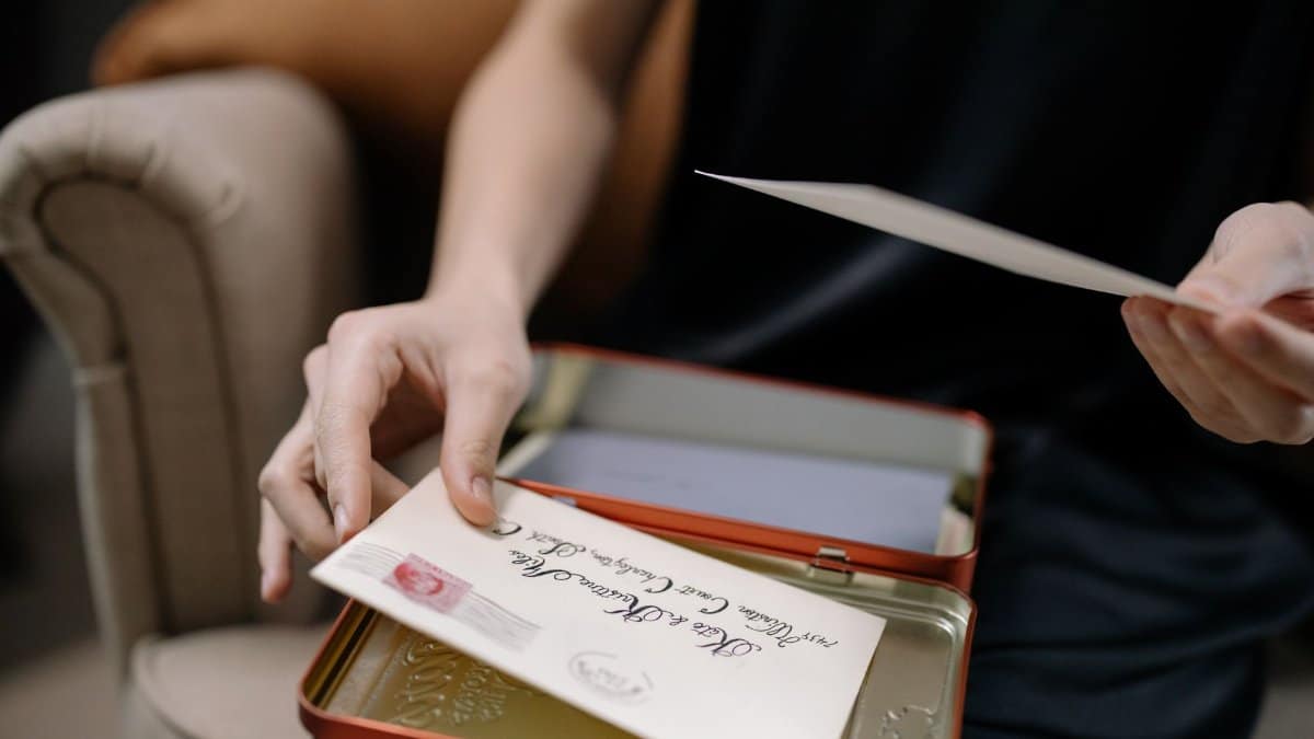 A person holds letters in a tin box, displaying vintage correspondence.