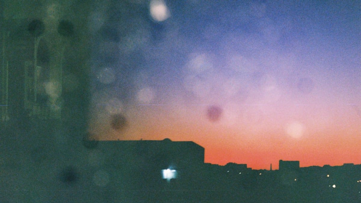 Abstract silhouette of cityscape against a vibrant sunset sky with bokeh lights.