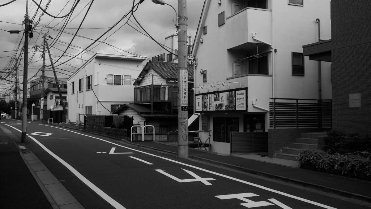 Black and white photograph of an empty street in Tokyo, Japan, capturing urban architecture and electric wires.