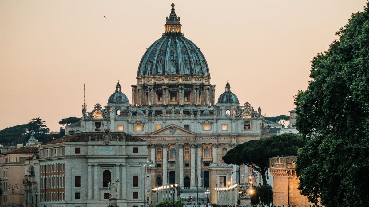 A stunning view of St. Peter's Basilica with a warm sunset backdrop in Vatican City.