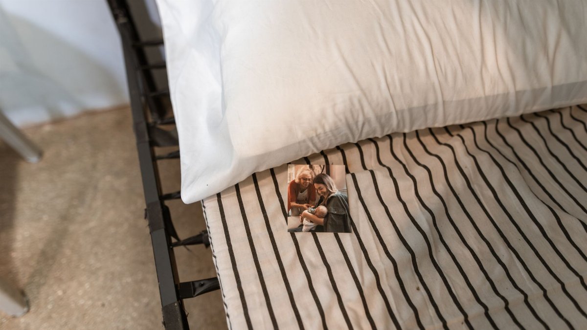 A high angle shot of a bed with striped sheets, a pillow, and a family photo.