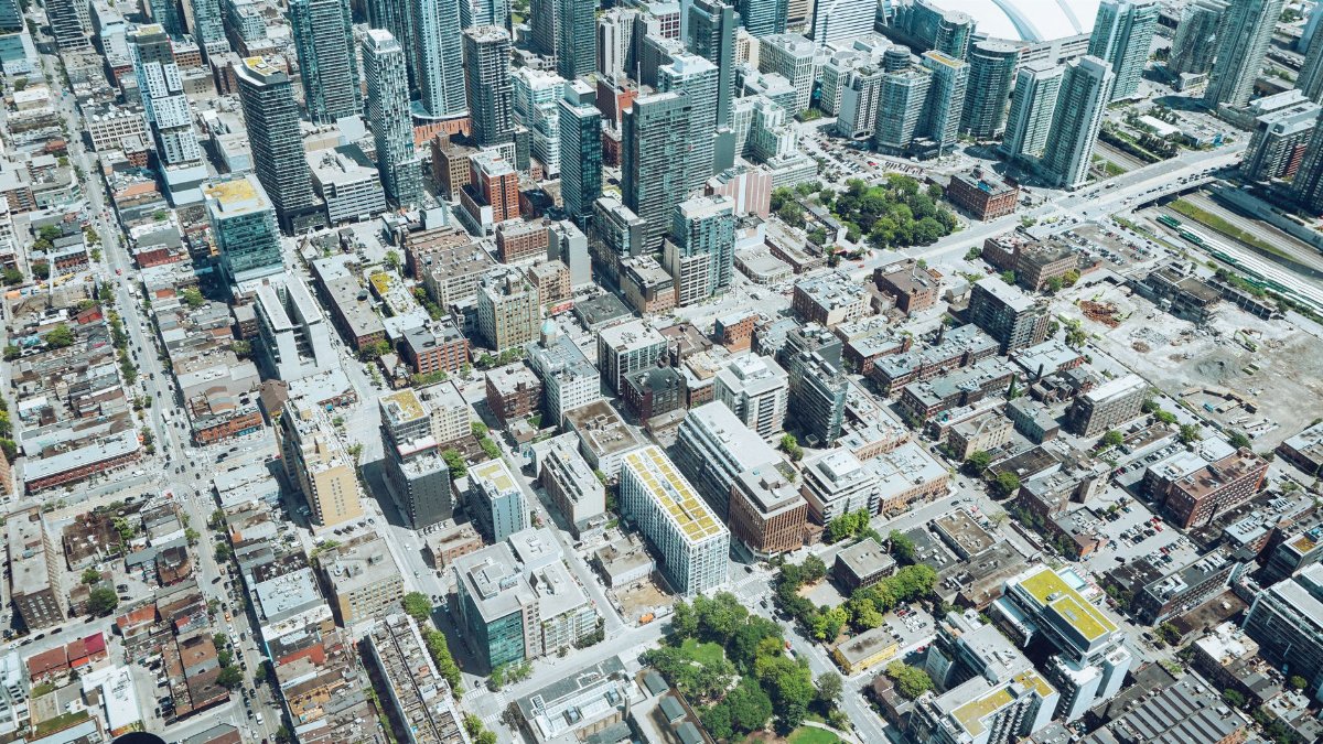 Drone view of modern big city with tall glass skyscrapers and high rise residential buildings on sunny summer day