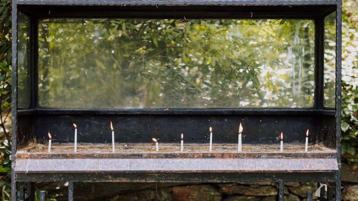 Candles burning in a shrine display case, İzmir, Türkiye, outdoor setting.