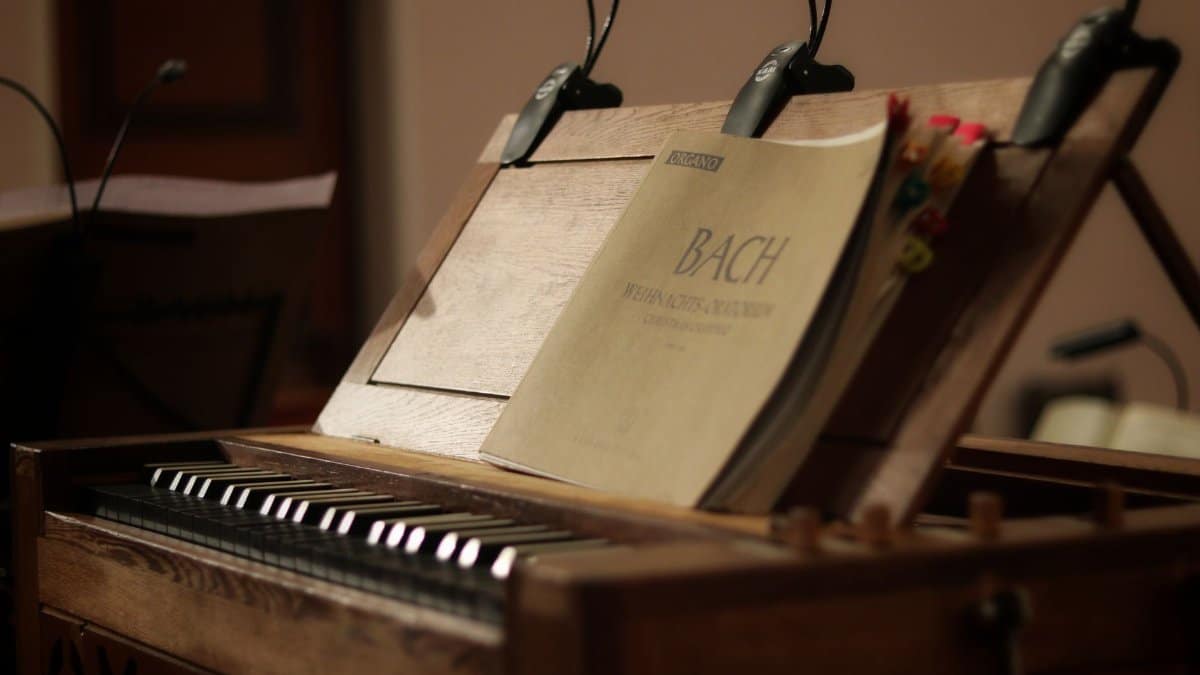 Close-up of a classic wooden organ with an open Bach music sheet, evoking nostalgia and history.