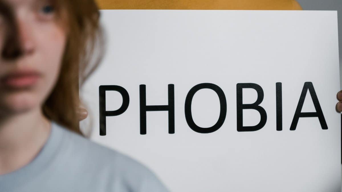 A close-up of a person holding a sign with the word 'Phobia,' illustrating mental health themes.