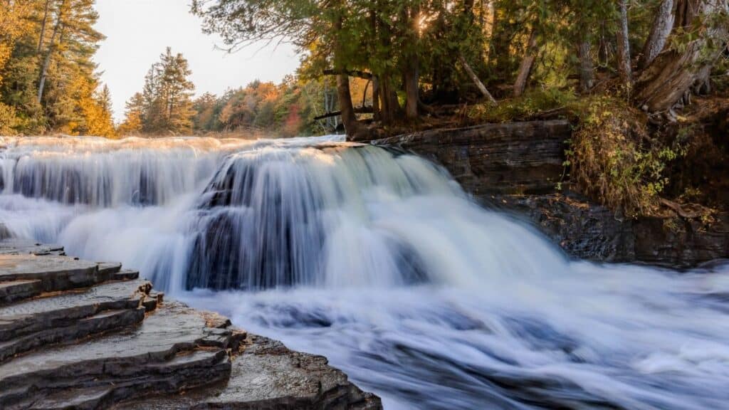 Capture of Tahquamenon Falls in Paradise, Michigan, showcasing autumn colors in a serene landscape.