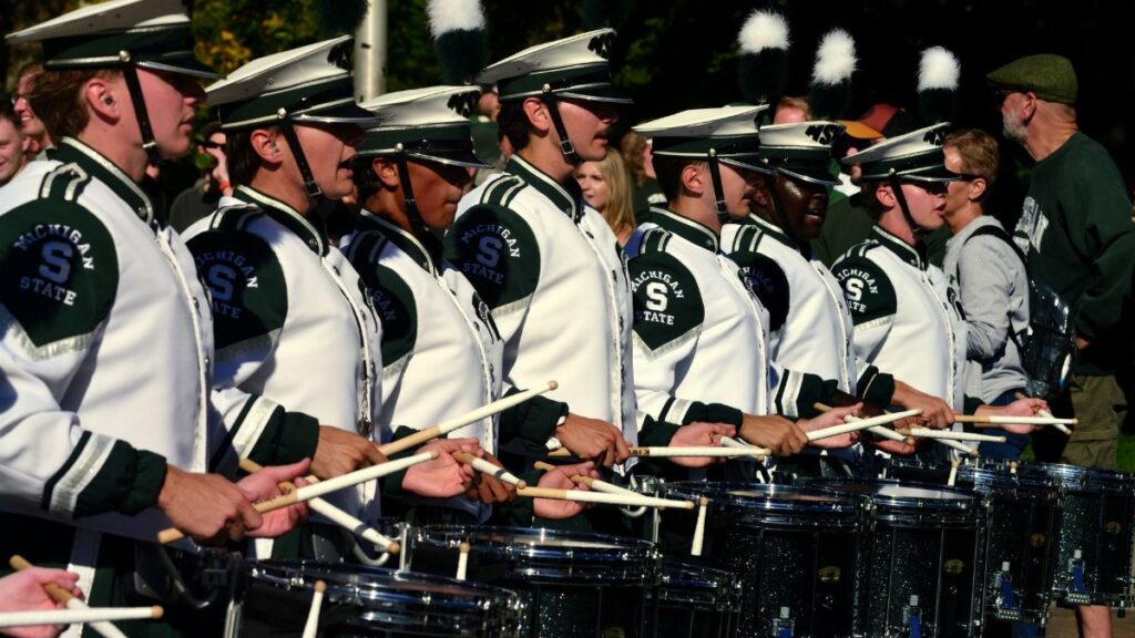 A vibrant outdoor image of the Michigan State University marching band drummers performing during a game day event.