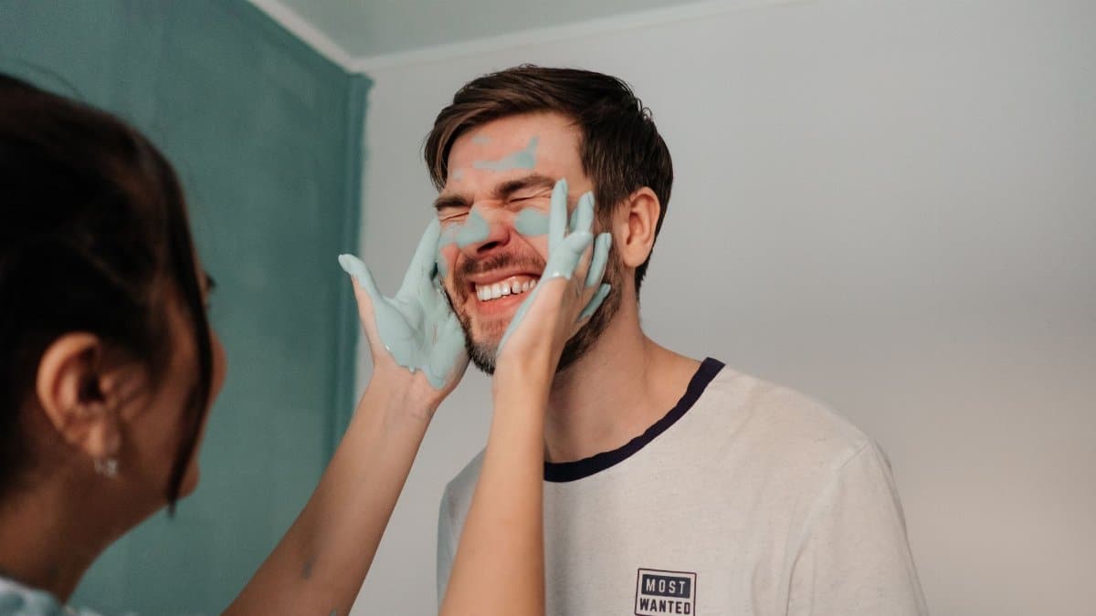 Fun and laughter as a couple playfully applies paint indoors, showcasing joy and closeness.