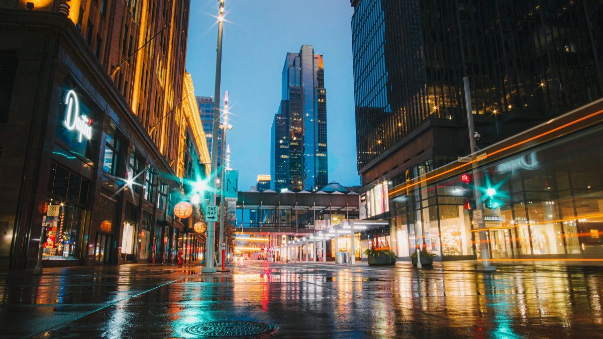 A vibrant view of the illuminated Minneapolis skyline at night with reflections on wet streets.
