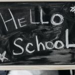 Close-up of hands holding a chalkboard with 'Hello School' message, perfect for back-to-school themes.