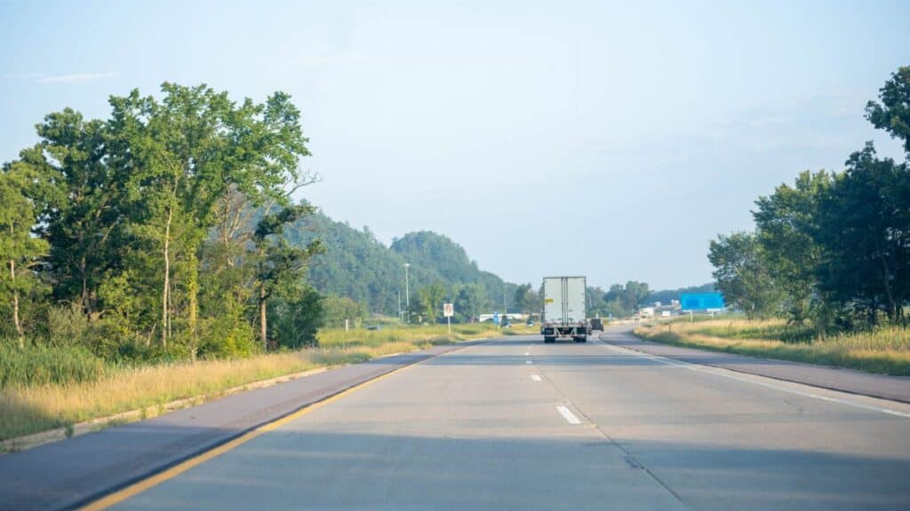 Tranquil highway scene with truck driving in Minnesota's lush summer landscape.
