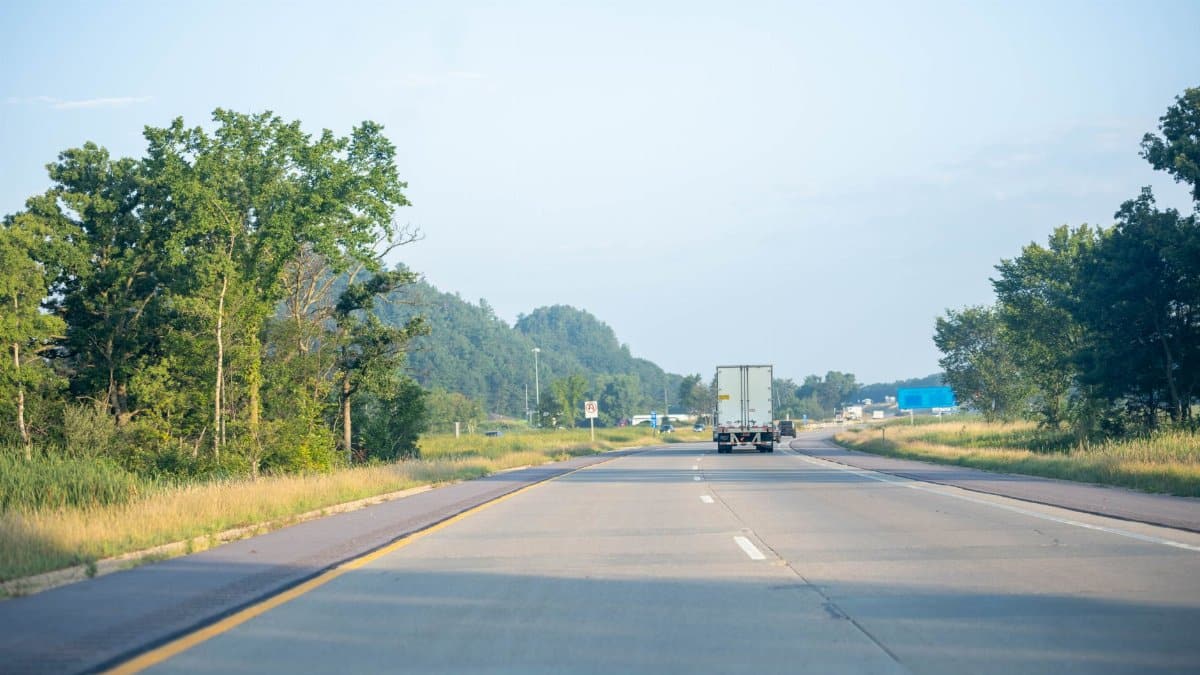 Tranquil highway scene with truck driving in Minnesota's lush summer landscape.