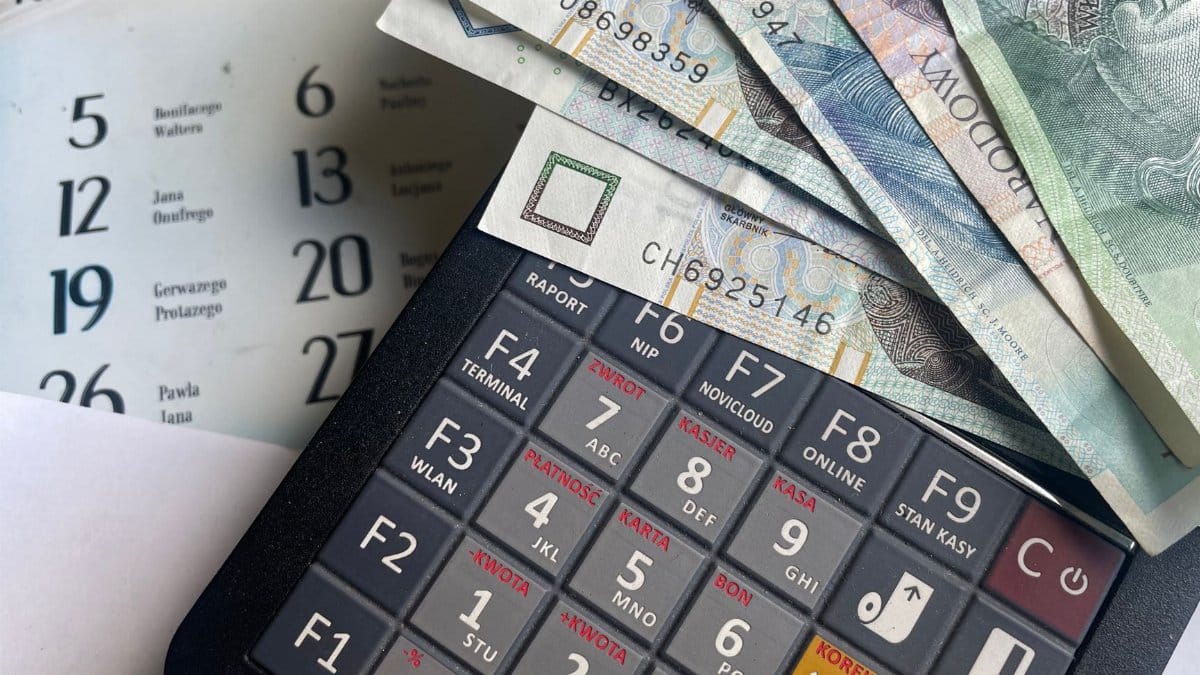 Close-up of Polish Zloty banknotes on a calculator with a calendar in the background.