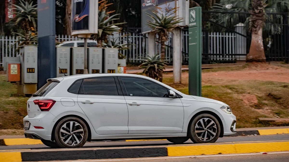 White car driving past urban area in Malkerns, Eswatini during the day.