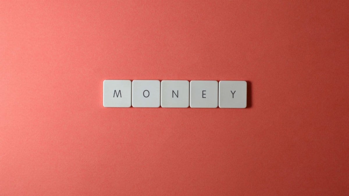 Minimalist layout showing word 'money' with letter tiles on a coral background.