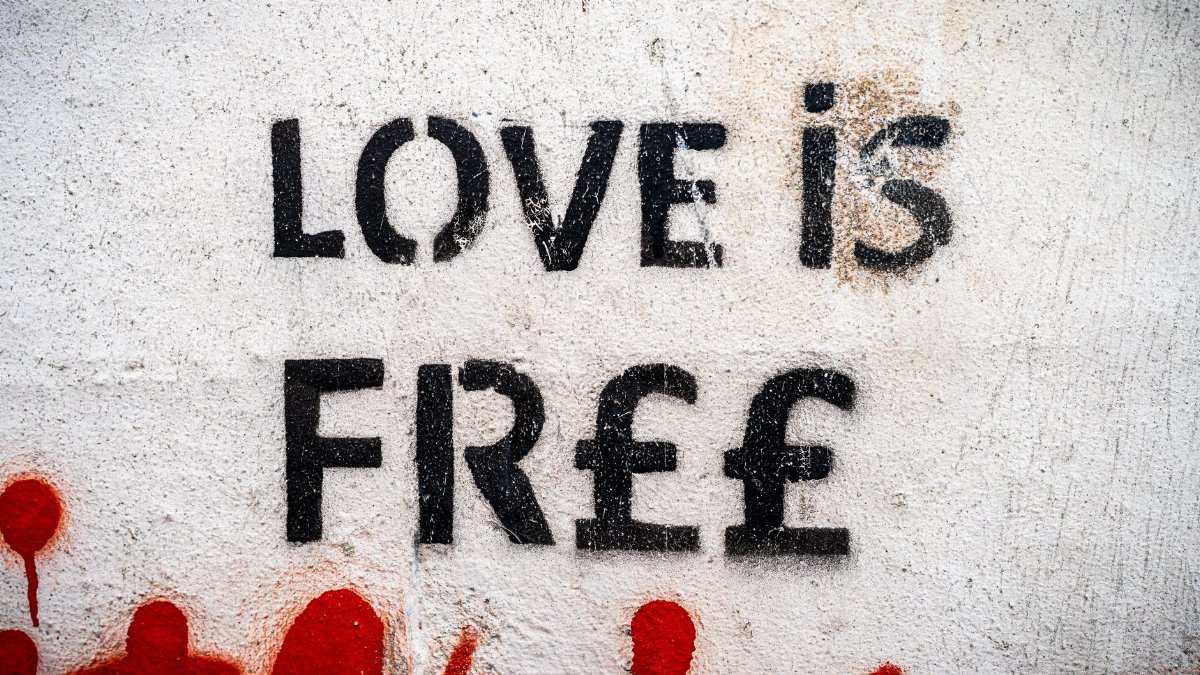 Street art featuring 'Love is Free' message stenciled on a wall.