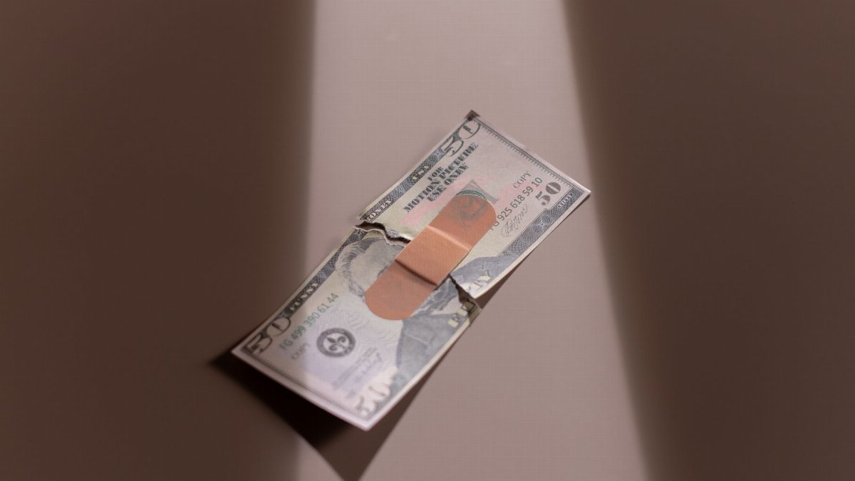 A $50 bill with a bandage symbolizes financial recovery and repair.
