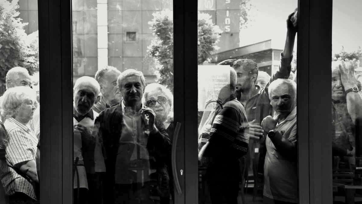 A monochrome photo capturing an elderly crowd through a glass door in Istanbul, Turkey.