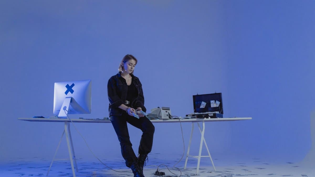 A woman in a dark room counting money with a computer and tools on a table.