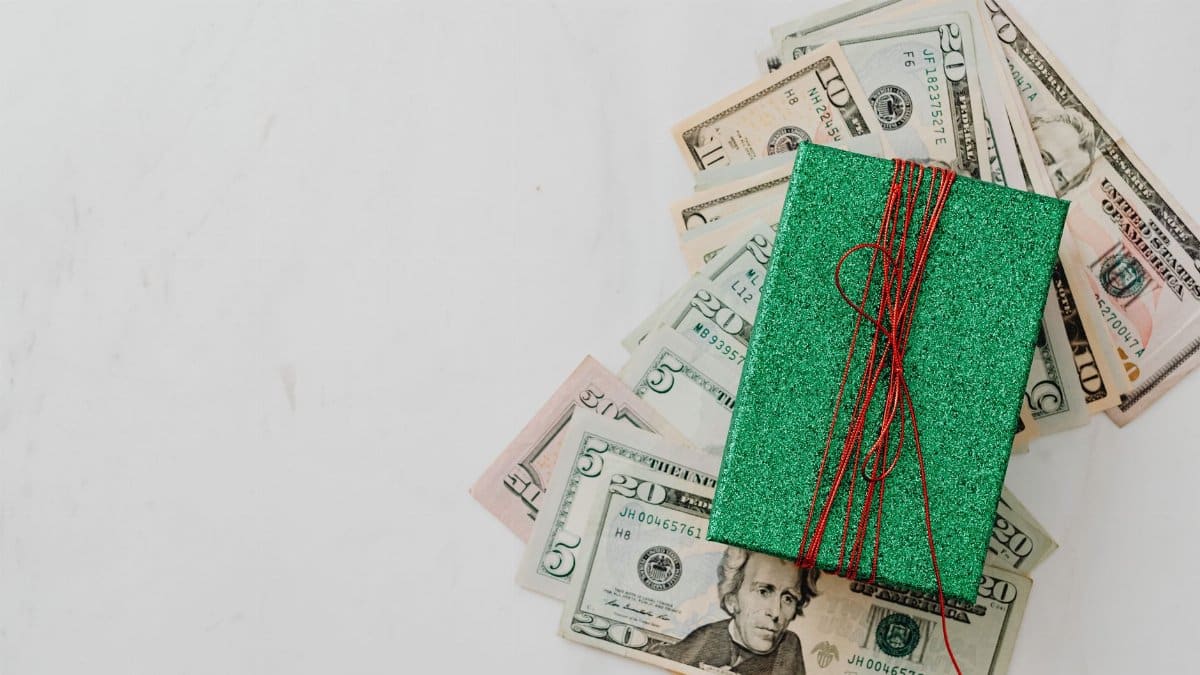 Green gift box on a pile of dollar banknotes showcasing a concept of monetary value and gift-giving.