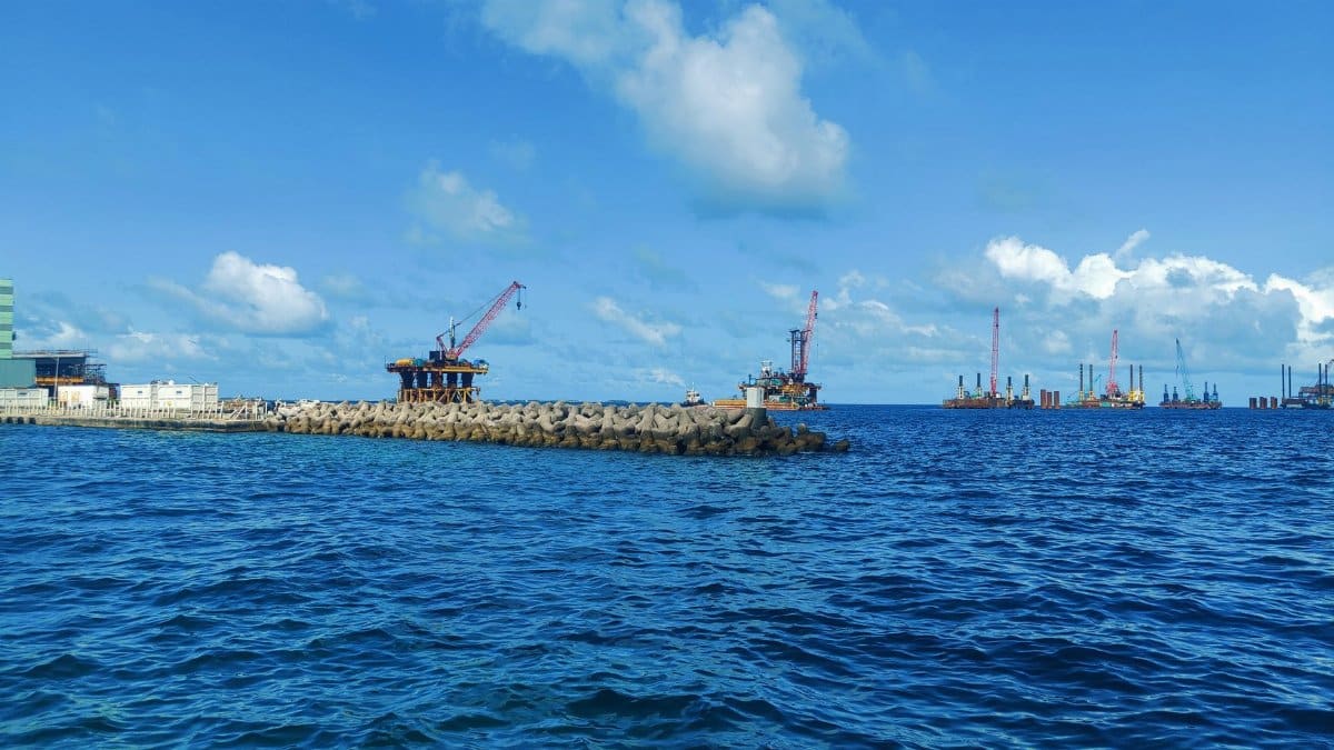 An offshore industrial platform with cranes in Maldives under a clear blue sky.