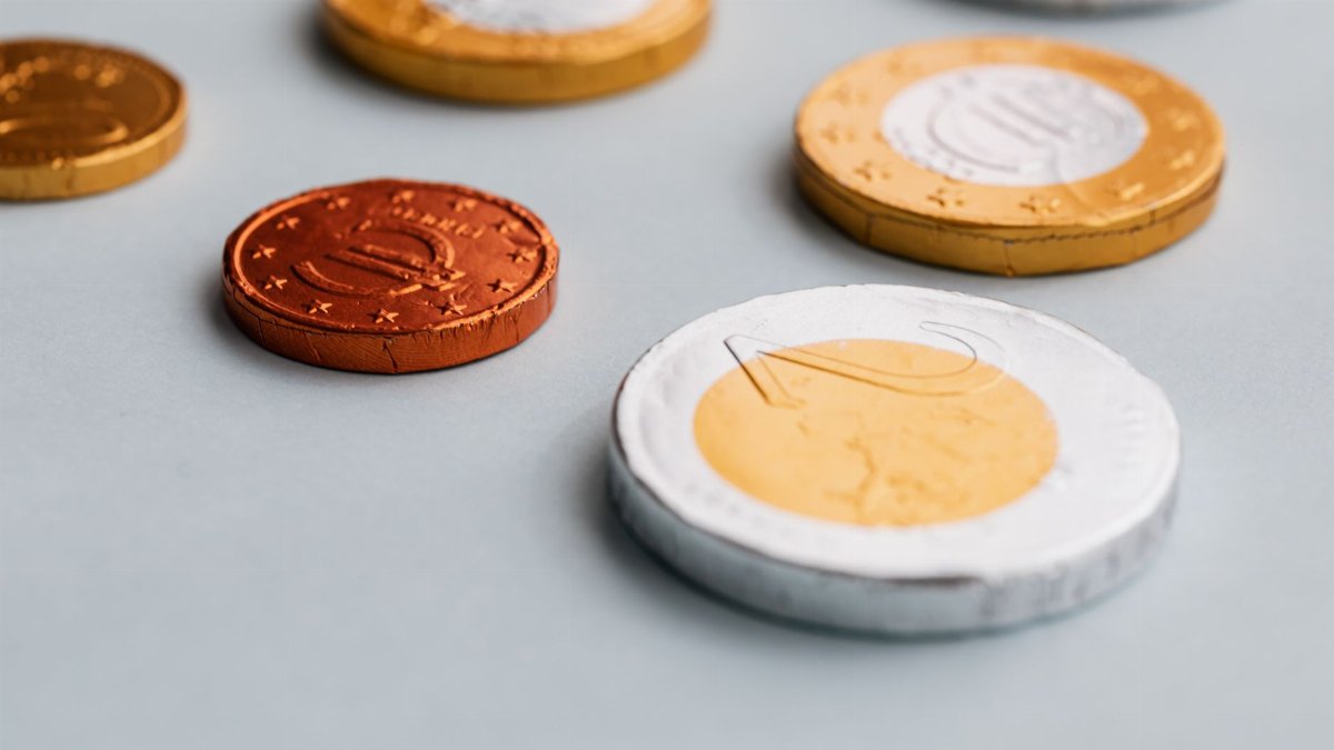 From above closeup of different size chocolate coins in foil package placed on white background