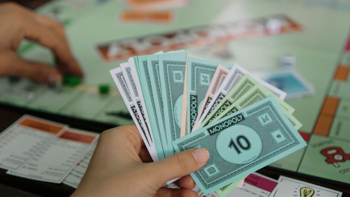 A close-up view of a person holding Monopoly money while playing the board game.